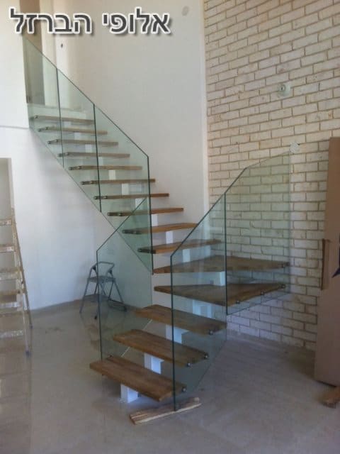 מעקה זכוכית מותקן על מדרגות ברזל עם חיפוי עץ בצבע טבעי. צילום: גיא